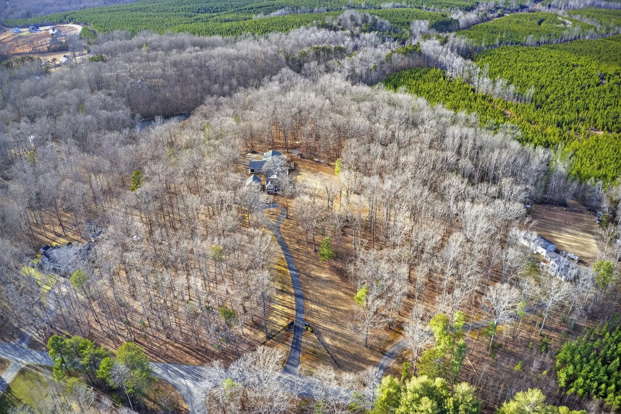Aerial view of wooded acreage with a creek and clearing cutting through the trees