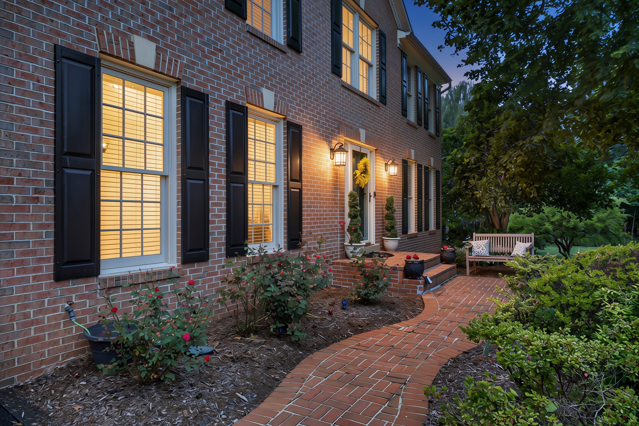 Brick colonial entry and walkway photographed at twilight with warm lighting