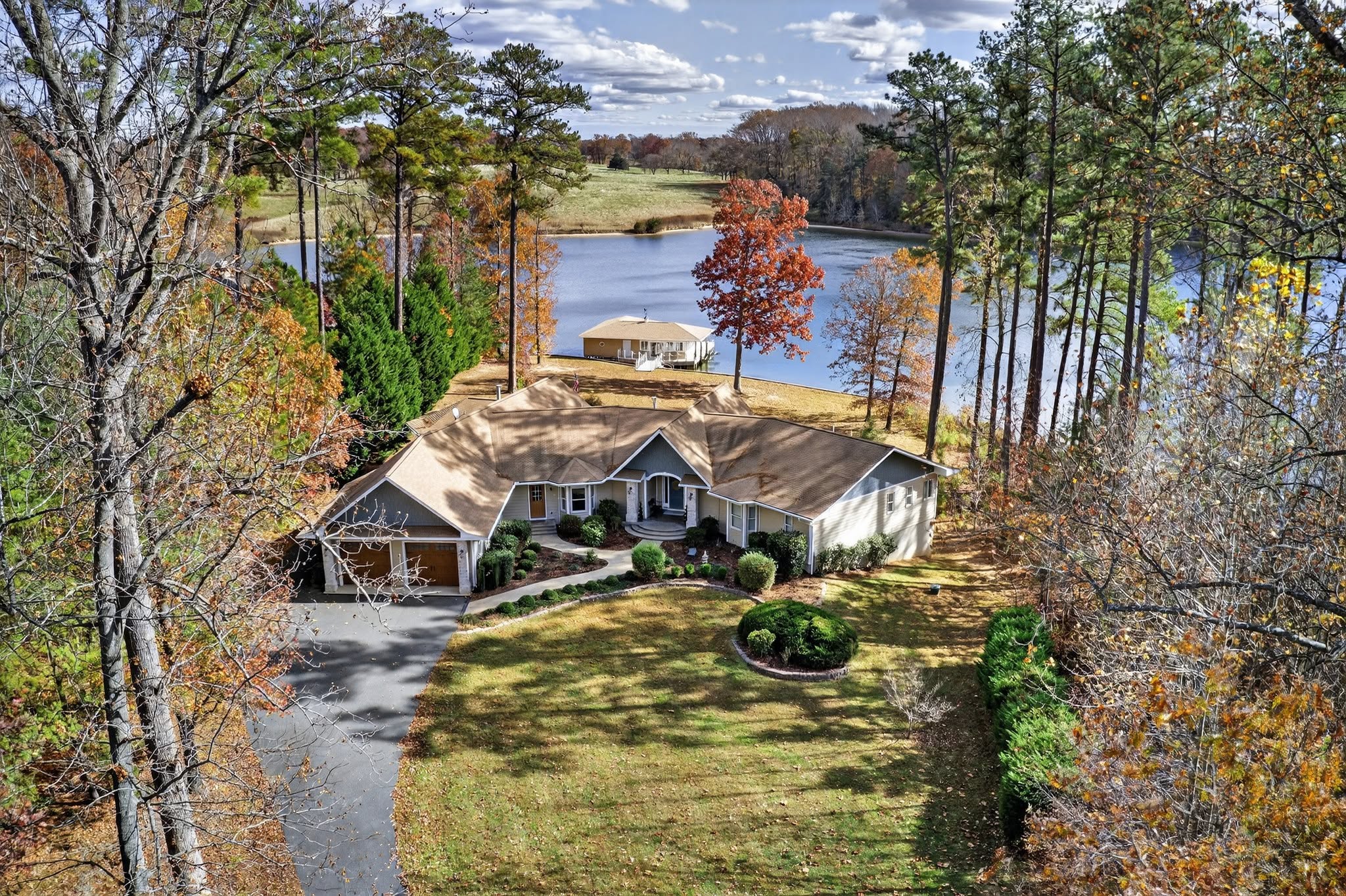 Aerial view of a lakefront home surrounded by autumn trees with a private dock