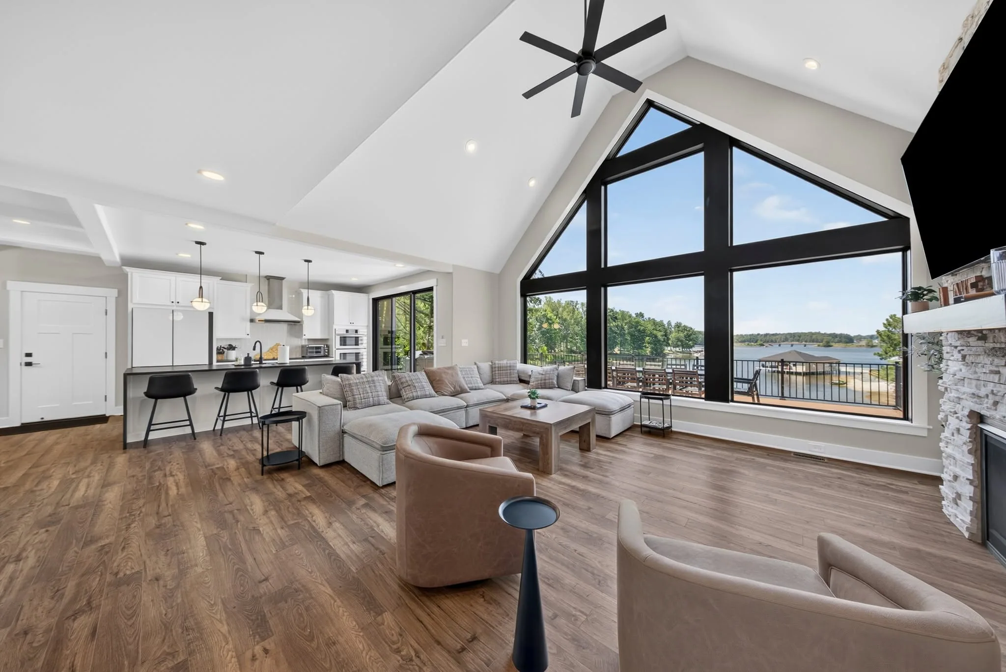 Vaulted great room with a wall of glass looking out over the lake and an open kitchen beyond