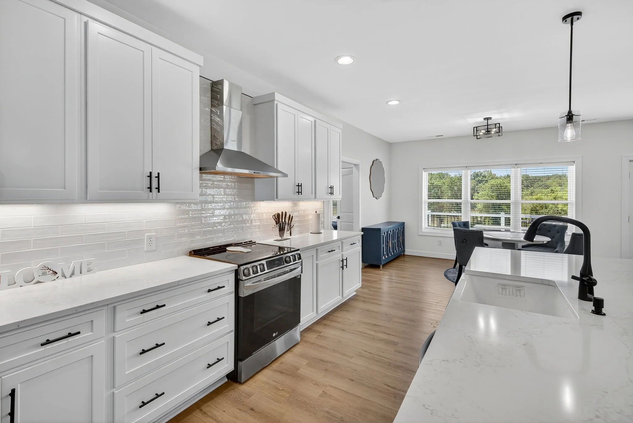 White shaker kitchen with quartz counters, stainless range and a navy island