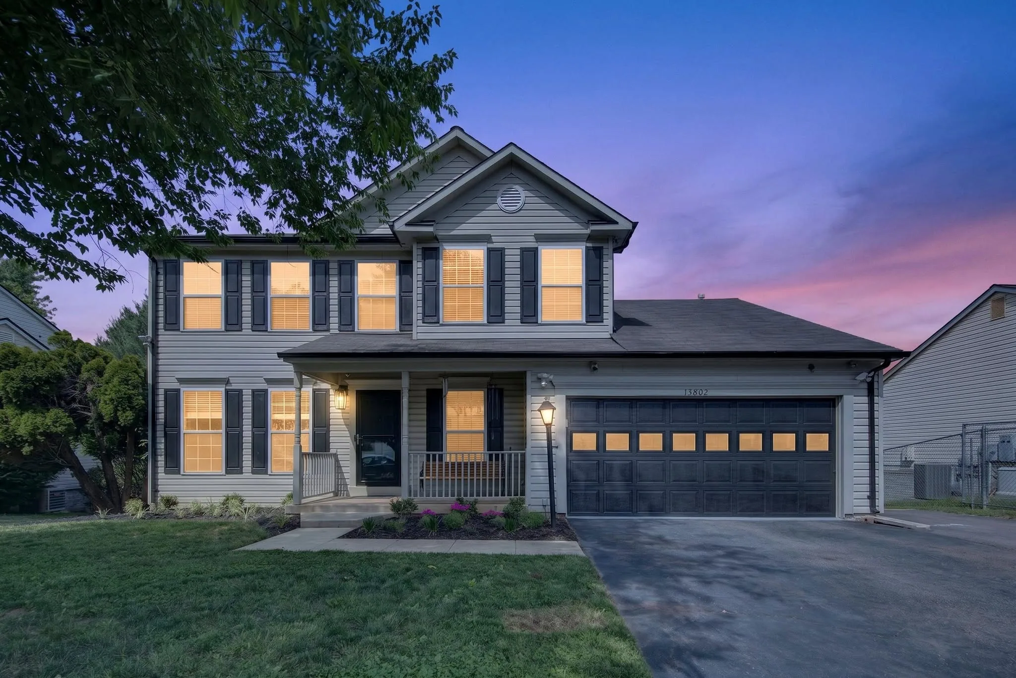 Virtual Twilight image of a two-story home with warm window light against a deep blue evening sky