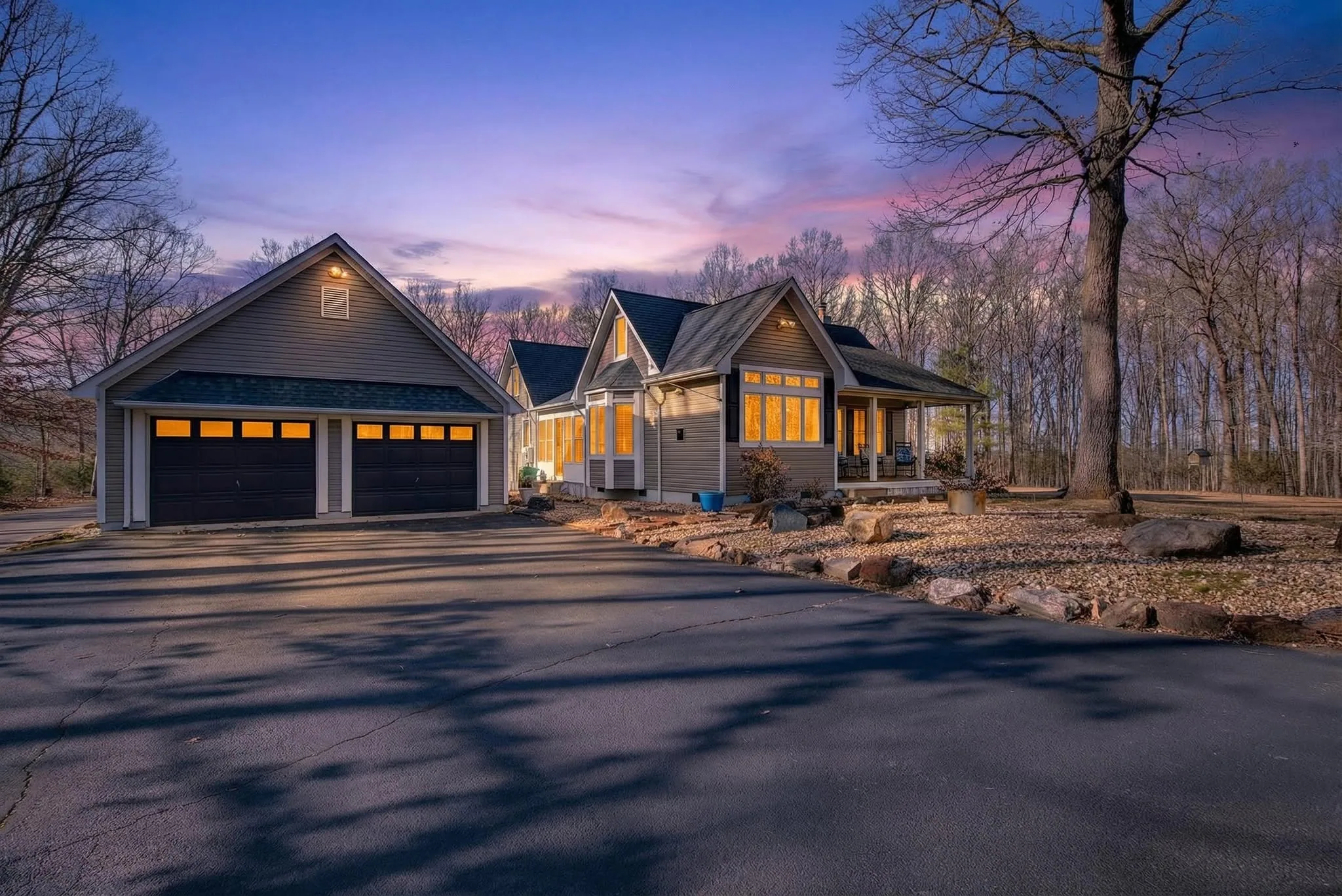 Virtual Twilight image of a contemporary home with a three-bay garage under a violet and pink sky