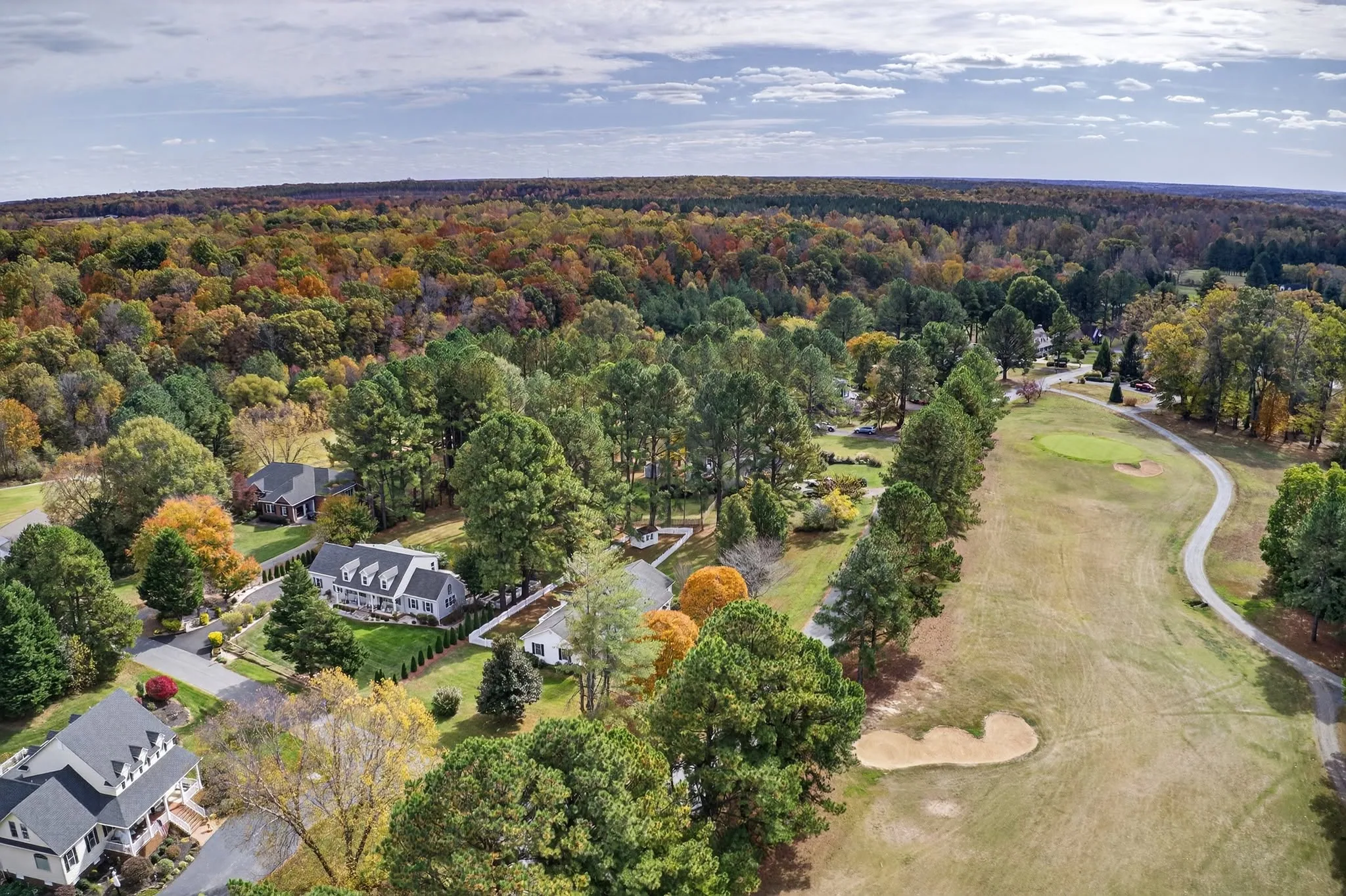 Aerial view of a residential golf community with homes bordering manicured fairways