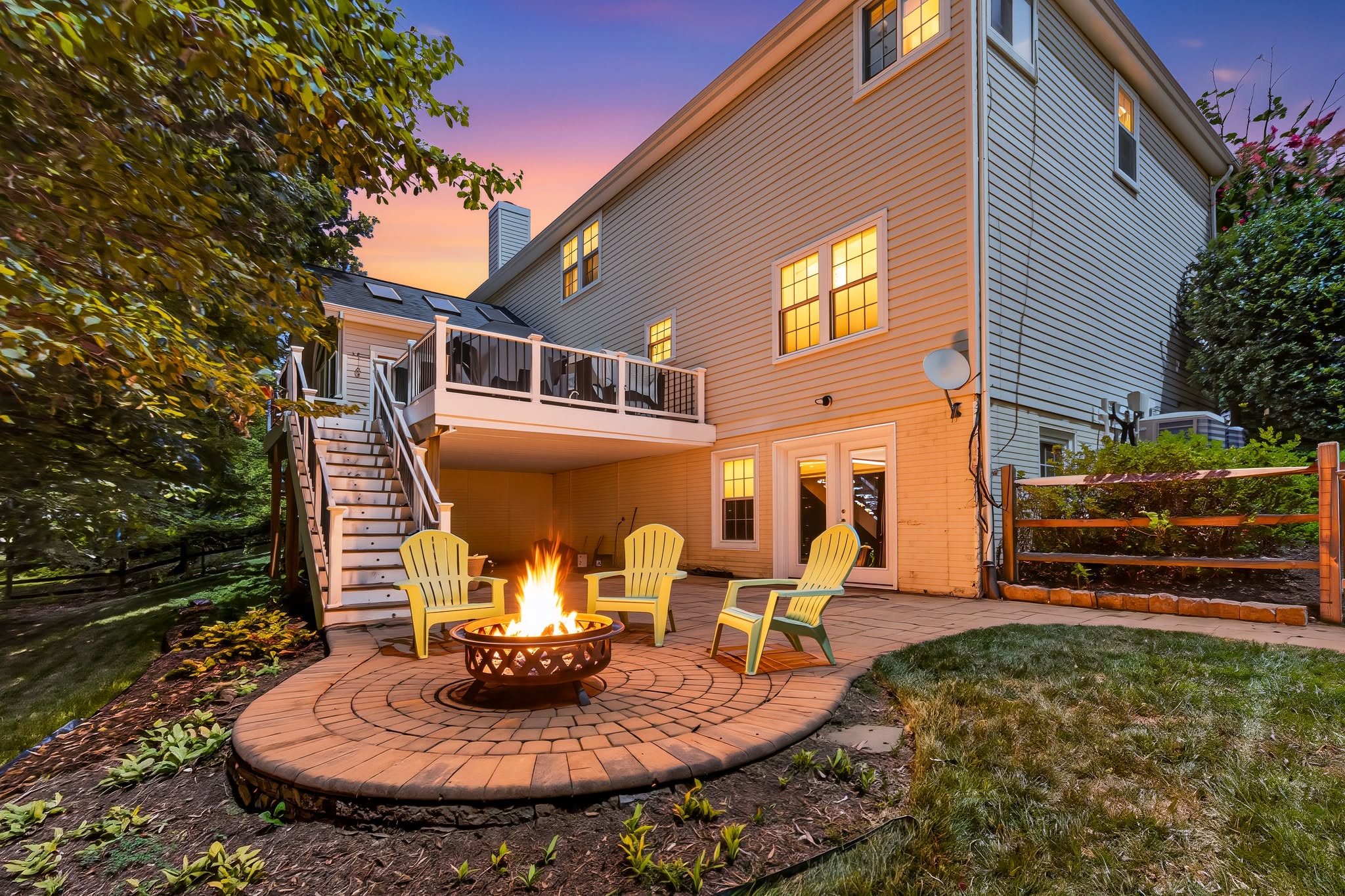 Rear deck and stone patio with a lit firepit at twilight