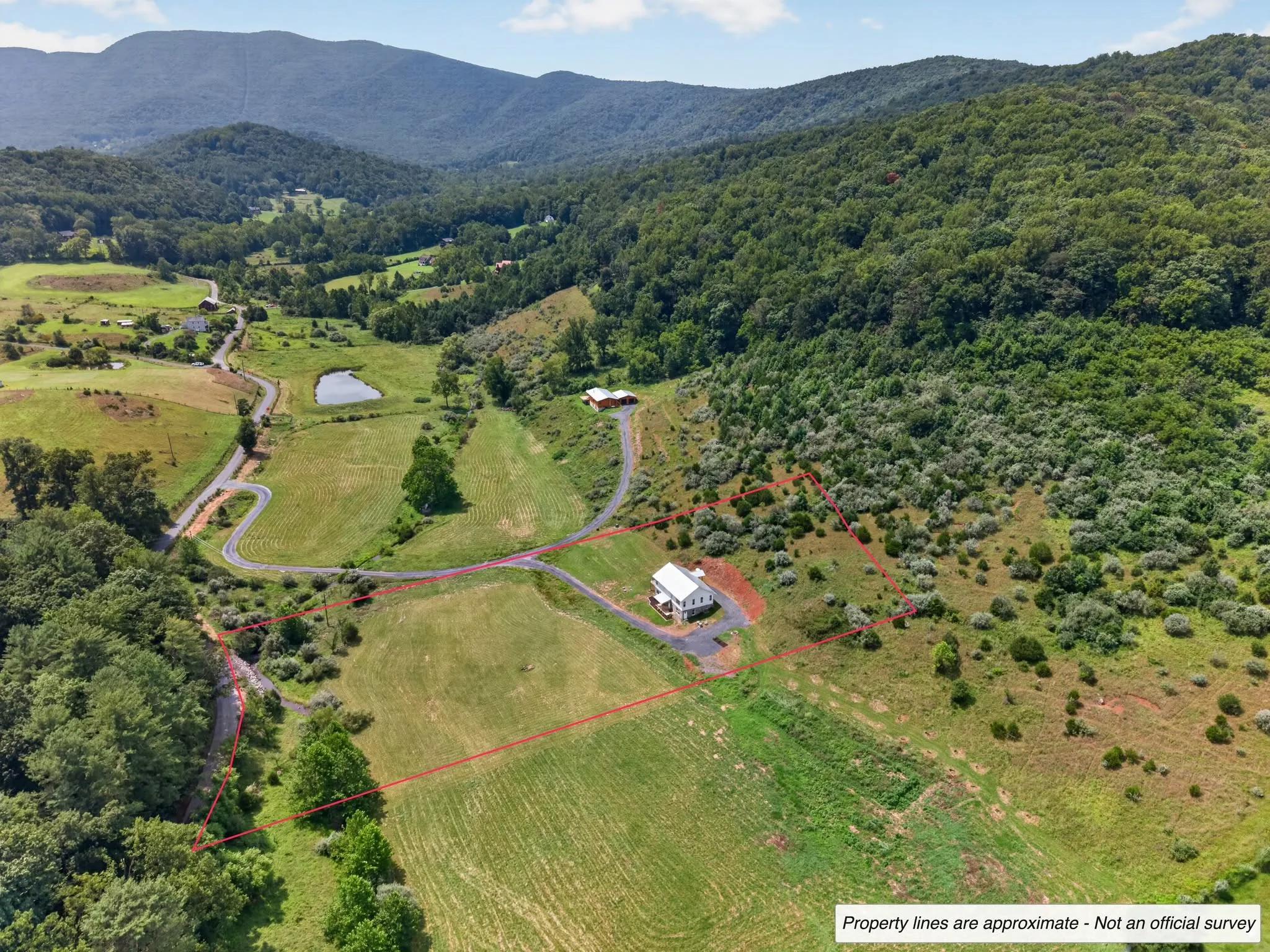 Aerial view of a rural mountain property with the approximate property boundary outlined in red.