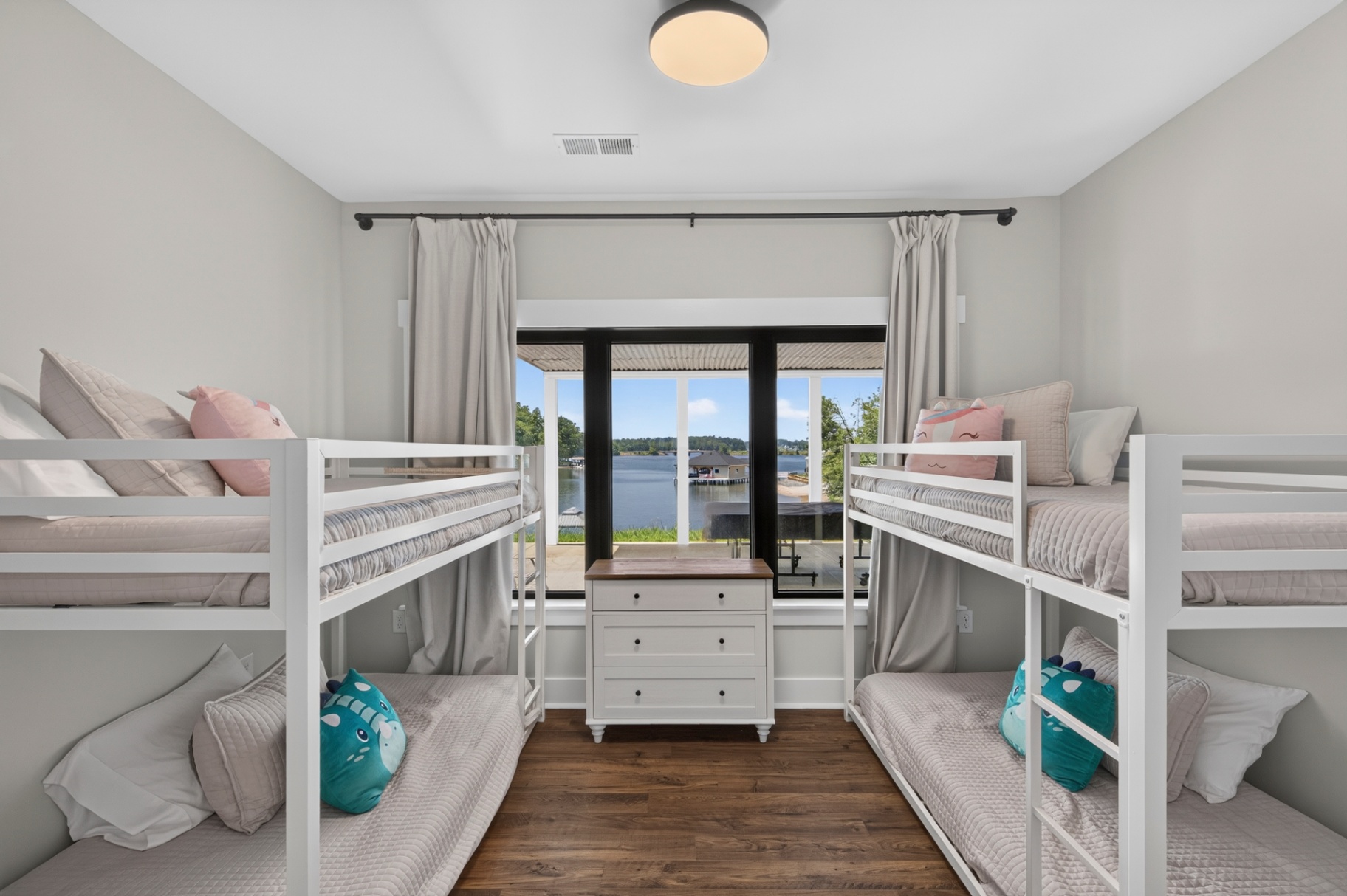 White bunk beds on either side of a window overlooking the lake